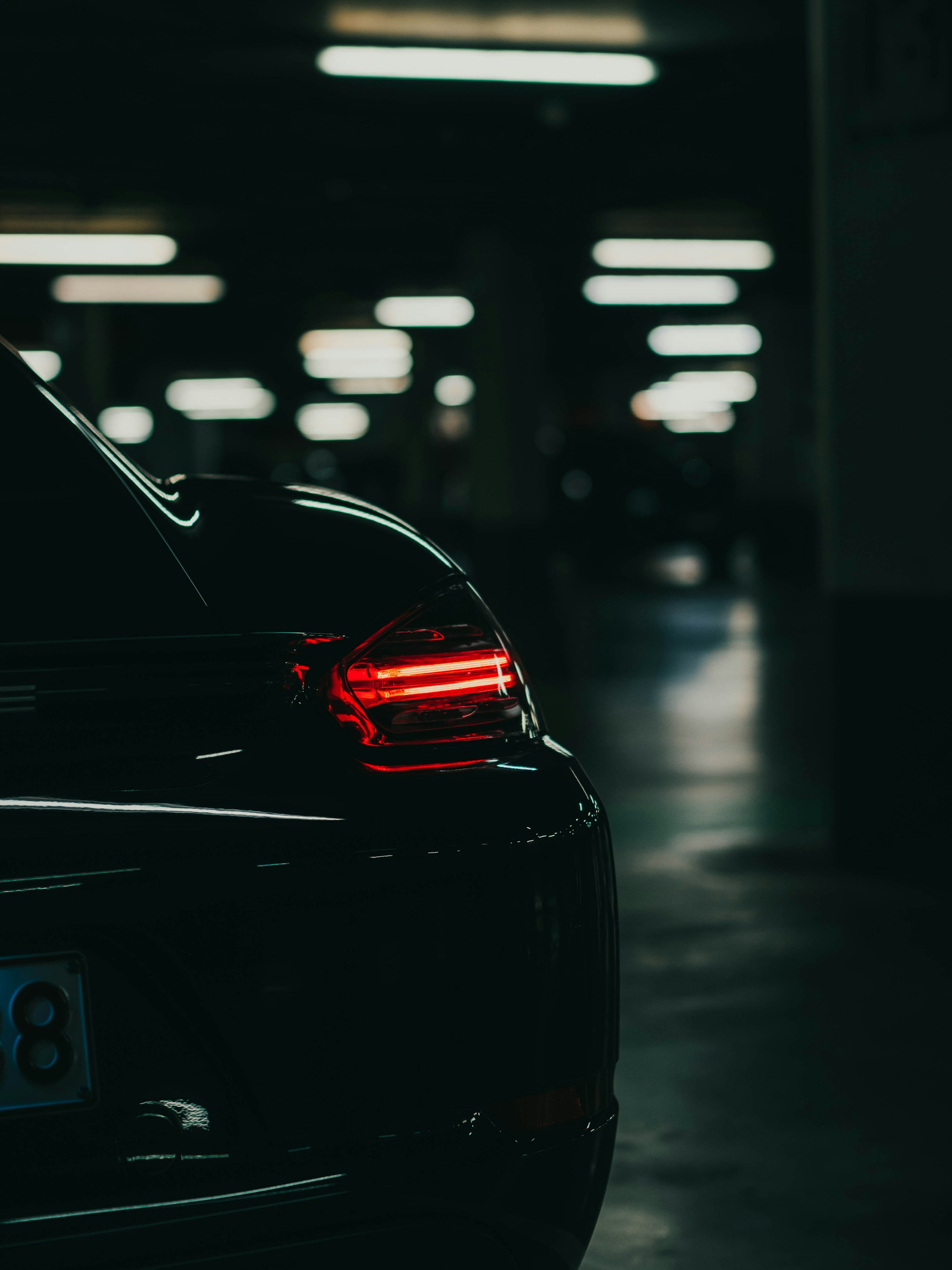 A dark sports car with illuminated rear lights in a garage